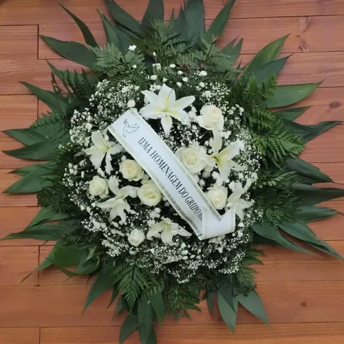 Coroa de flores 3002 brancas para funeral com lírios, rosas e folhagens naturais, faixa de homenagem escrita "Uma homenagem do grupo".